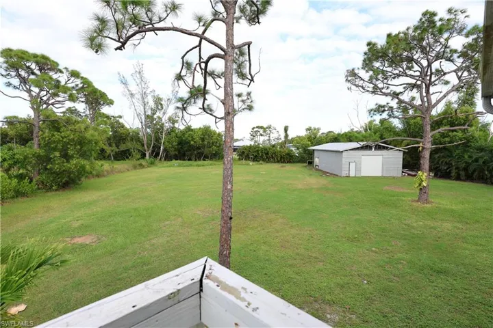 View of grassy yard with an outdoor structure and a balcony