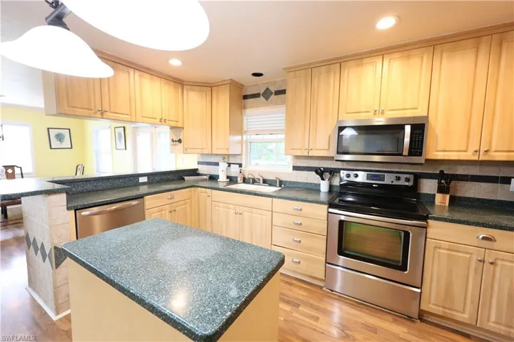 Kitchen featuring appliances with stainless steel finishes, light brown cabinets, light wood-style flooring, a center island, and a peninsula