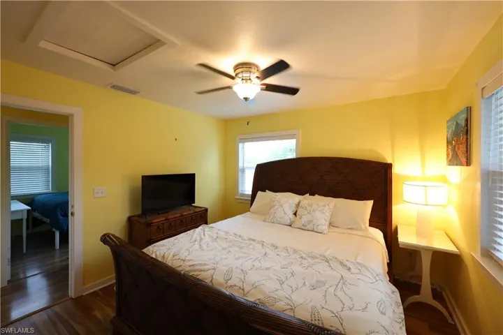 Bedroom featuring dark wood-style floors, attic access, and ceiling fan