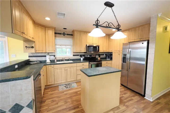 Kitchen featuring appliances with stainless steel finishes, a center island, pendant lighting, light wood-type flooring, and recessed lighting