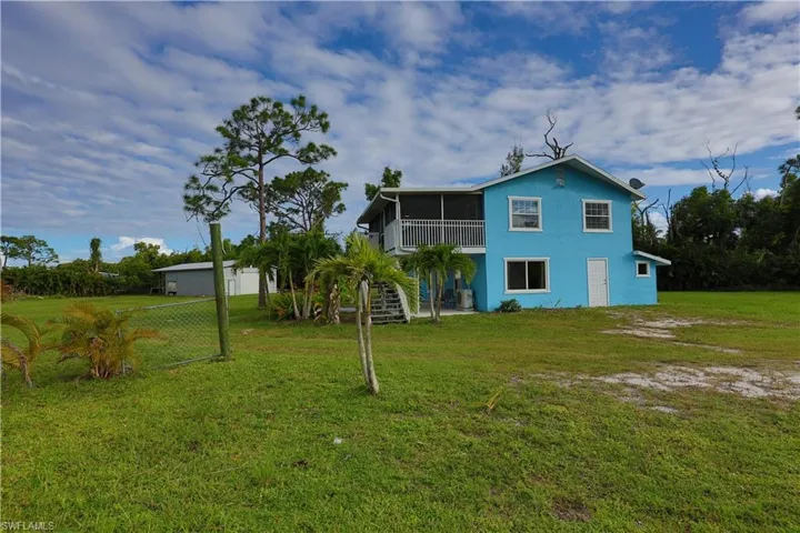 Rear view of property featuring stairway, a sunroom, a yard, stucco siding, and a patio area