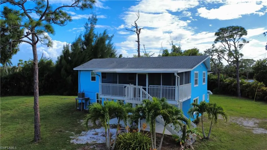 View of front of home with a front yard, stairs, roof with shingles, and a porch