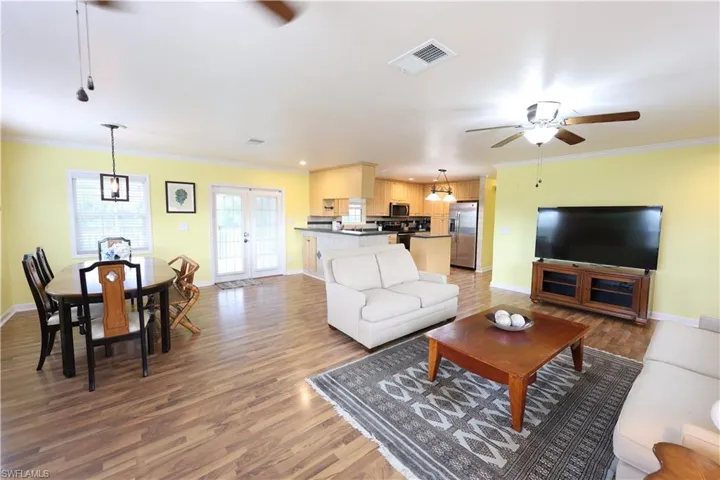 Living room featuring a ceiling fan, ornamental molding, light wood-type flooring, and french doors