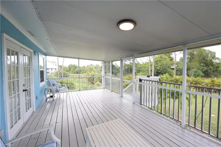 Wooden terrace with french doors, view of scattered trees, and a lawn
