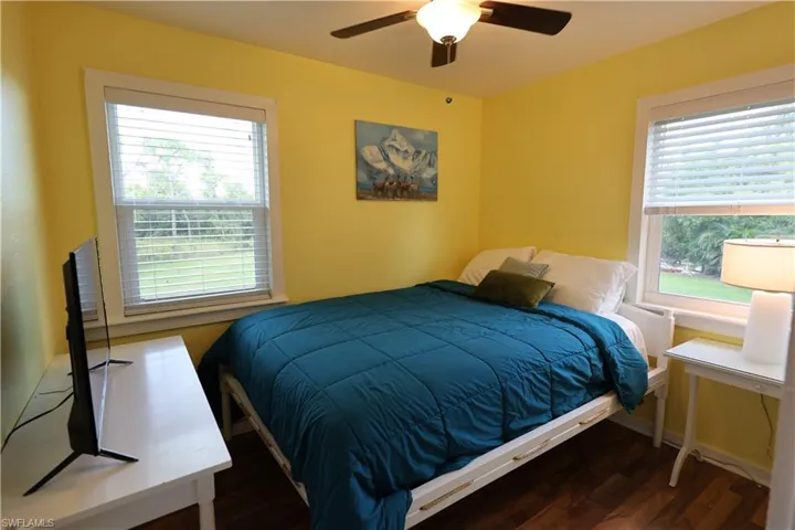 Bedroom with wood finished floors, a ceiling fan, and multiple windows