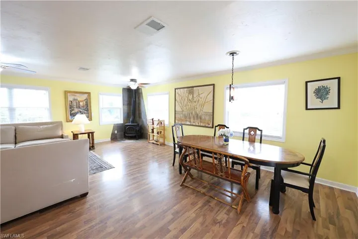 Dining area featuring a wood stove, crown molding, and wood finished floors