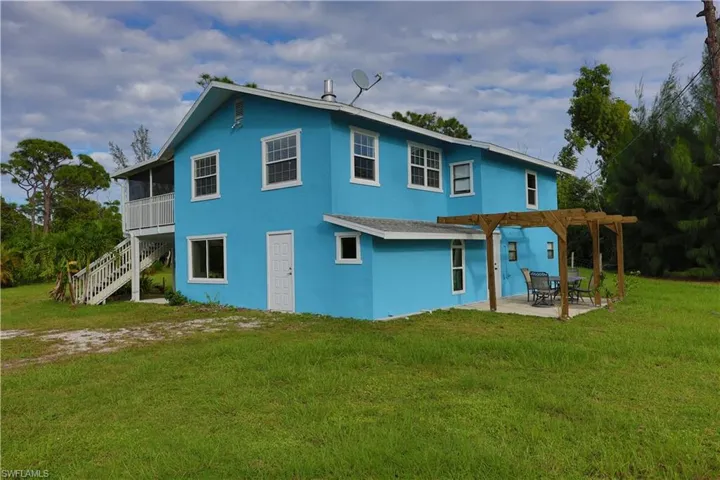 Rear view of property featuring a yard, stucco siding, stairway, and a patio