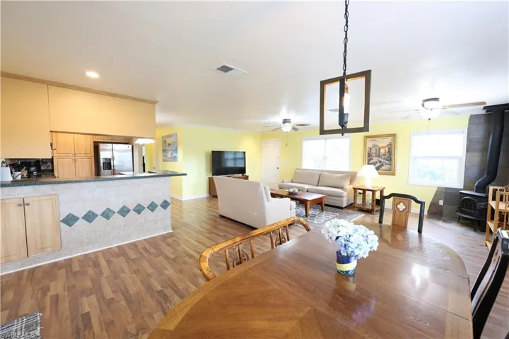 Dining room with a wood stove, dark wood-type flooring, ornamental molding, and ceiling fan