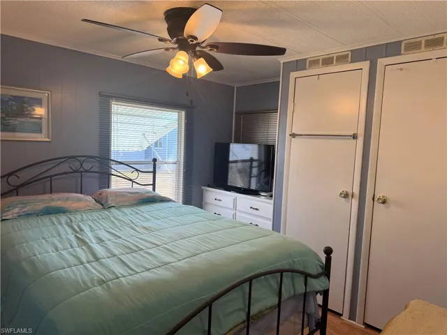 Bedroom with a ceiling fan, light wood-style flooring, a closet, ornamental molding, and a textured ceiling