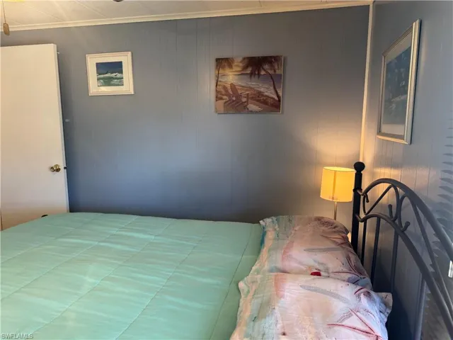 Bedroom with ornamental molding and wooden walls