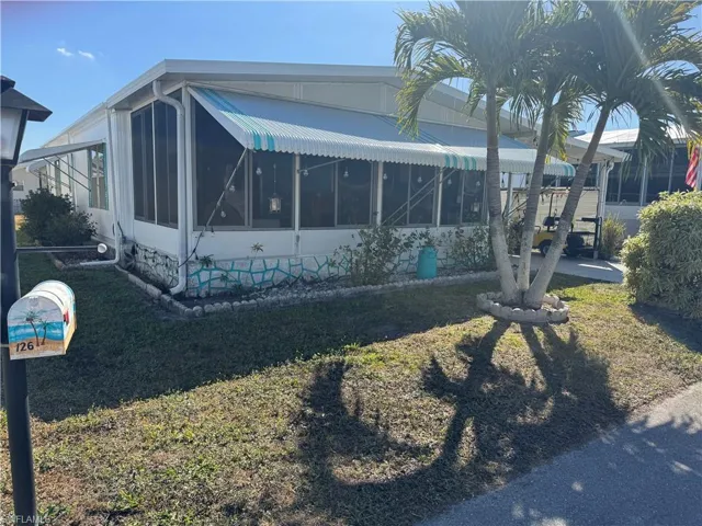 View of home's exterior with a sunroom and a yard