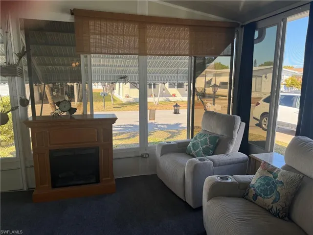 Living room featuring a fireplace, dark carpet, and lofted ceiling