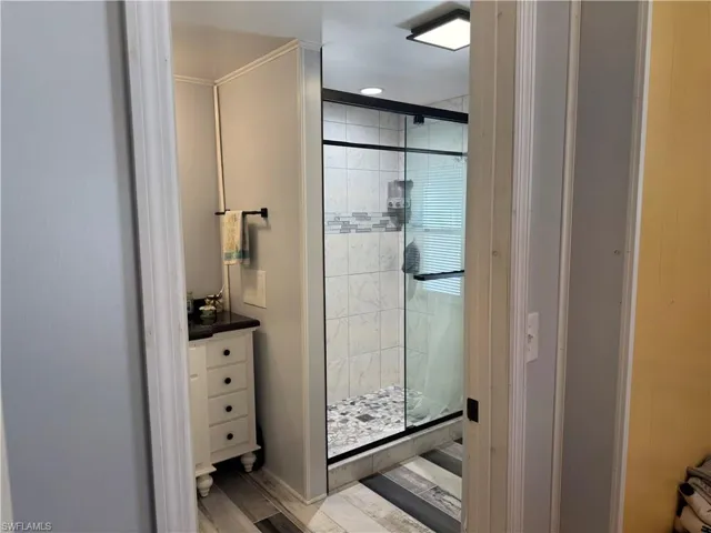 Full bath featuring a shower stall, vanity, and light wood-style floors