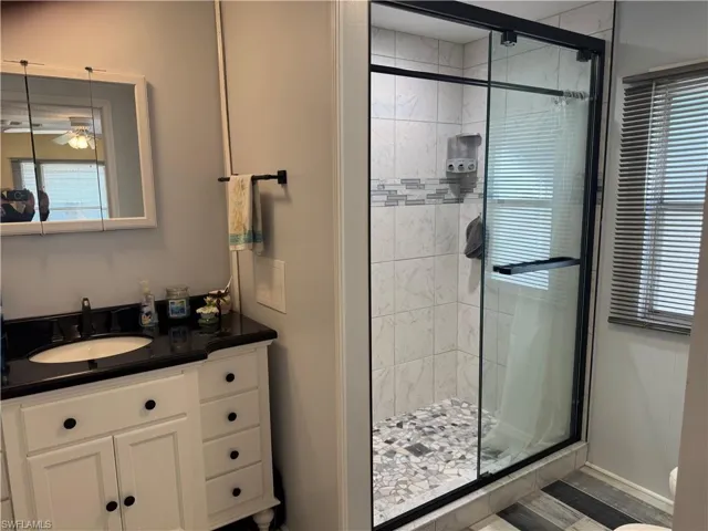 Bathroom featuring a stall shower, vanity, and a ceiling fan