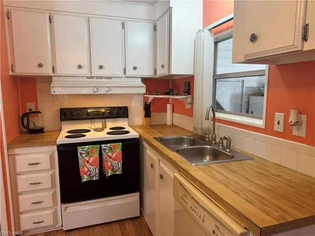Kitchen with range with electric stovetop, light countertops, dishwasher, backsplash, and white cabinetry