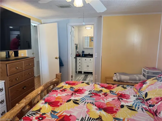 Bedroom featuring ornamental molding, ceiling fan, ensuite bathroom, and wood finished floors