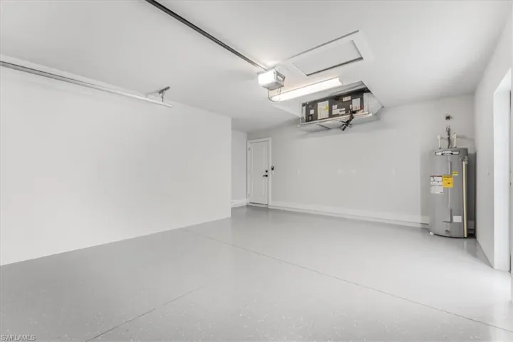 Garage featuring electric water heater and a garage door opener