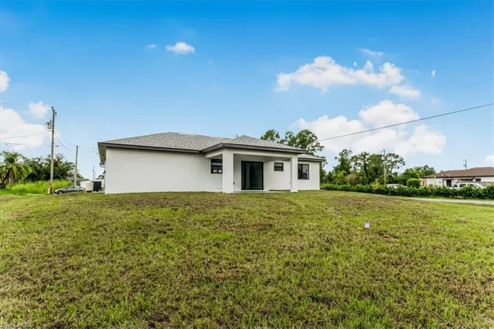 Back of house featuring stucco siding and a lawn
