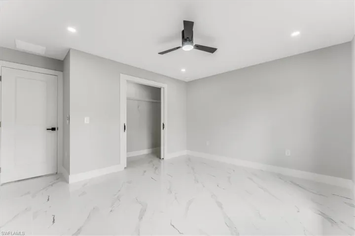 Unfurnished bedroom featuring recessed lighting, ceiling fan, a closet, and light marble finish flooring