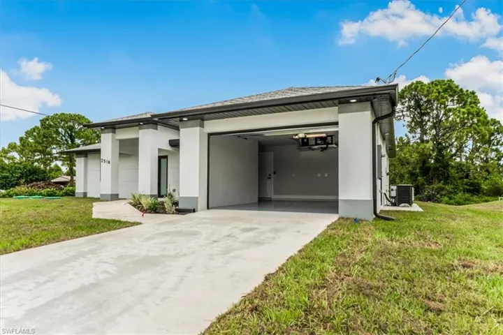 View of front of home featuring driveway, stucco siding, a front lawn, and a garage