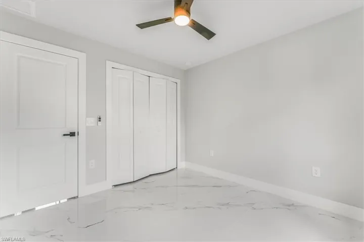 Unfurnished bedroom featuring marble finish floors, a closet, and ceiling fan