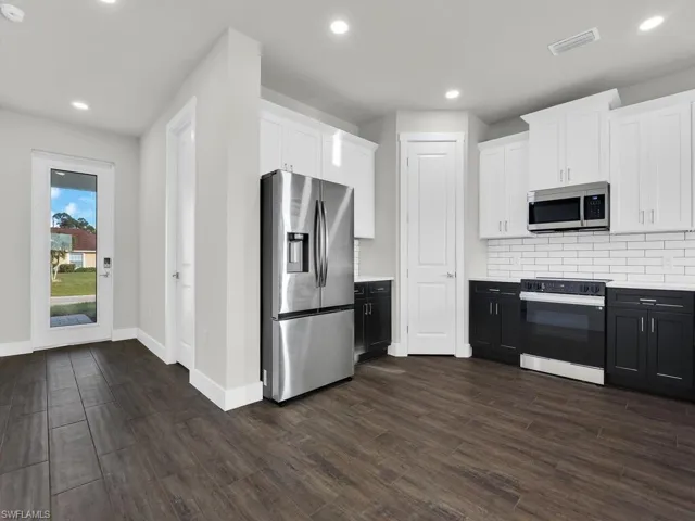 Kitchen with white cabinetry, appliances with stainless steel finishes, tasteful backsplash, recessed lighting, and dark wood-type flooring