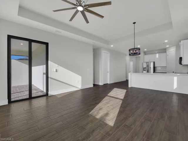 Unfurnished living room featuring a raised ceiling, recessed lighting, wood tiled floors, and ceiling fan