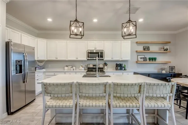 Kitchen with stainless steel appliances, an island with sink, a kitchen bar, white cabinets
