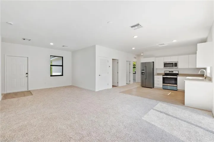 Kitchen featuring stainless steel appliances, visible vents, light carpet, and white cabinetry