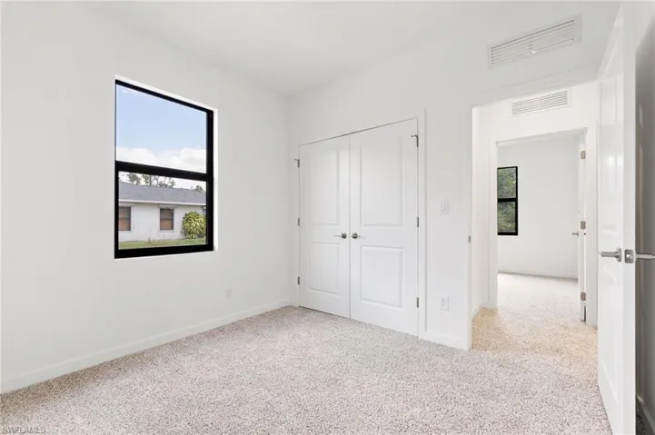 Unfurnished bedroom with carpet floors, baseboards, visible vents, and a closet