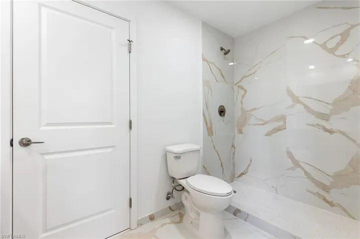 Bathroom featuring a marble finish shower and toilet