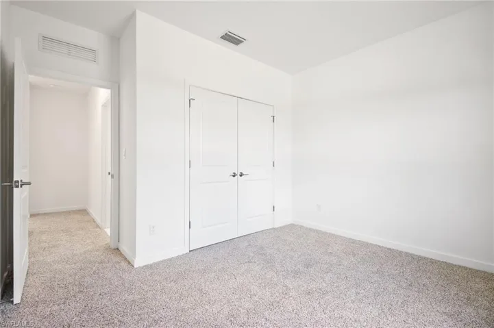 Unfurnished bedroom with carpet floors, a closet, and visible vents