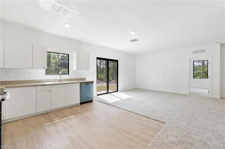 Kitchen featuring a sink, stainless steel dishwasher, white cabinetry, and visible vents