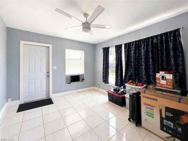 Open living space featuring light-toned tile flooring and pale blue wainscoting