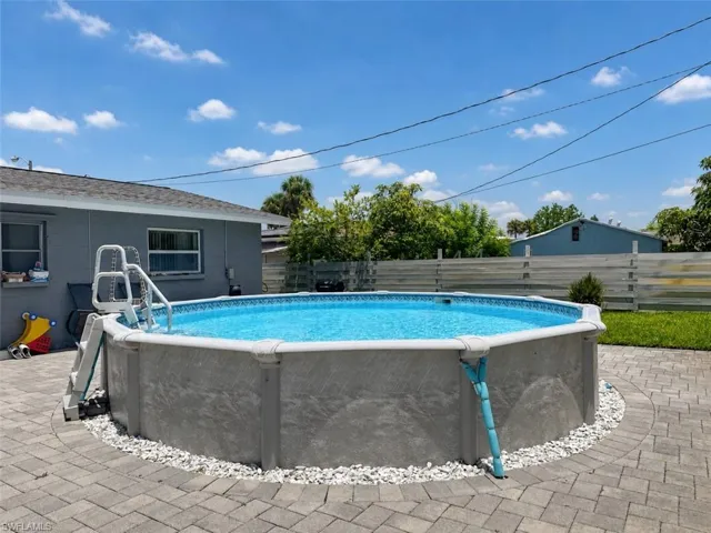 Above-ground pool with surrounding paver patio and white stone accents