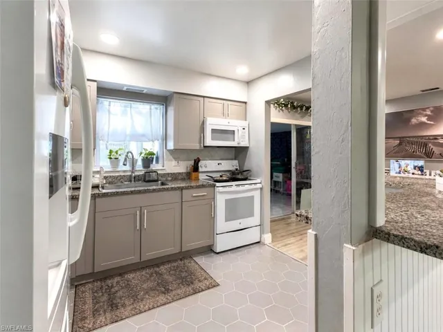Kitchen featuring hexagon tile flooring, light gray cabinetry, a white microwave, a white range, and a window above the sink