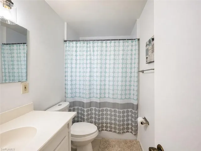 Bathroom featuring a white vanity with an integrated sink, a rectangular mirror, and an overhead light fixture