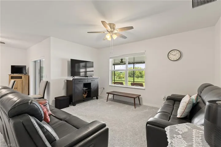 Living room with ceiling fan and light colored carpet