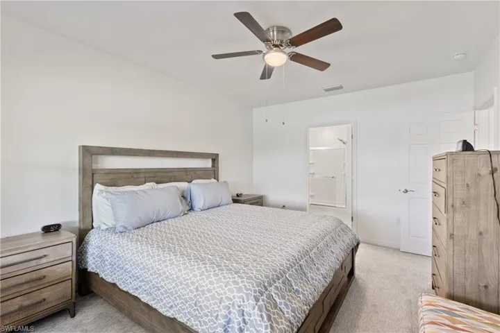 Carpeted bedroom featuring ceiling fan and connected bathroom