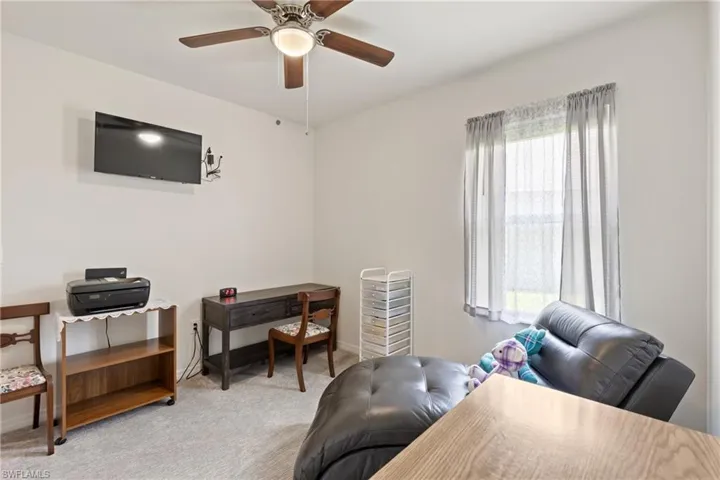 Home office with light carpet and ceiling fan