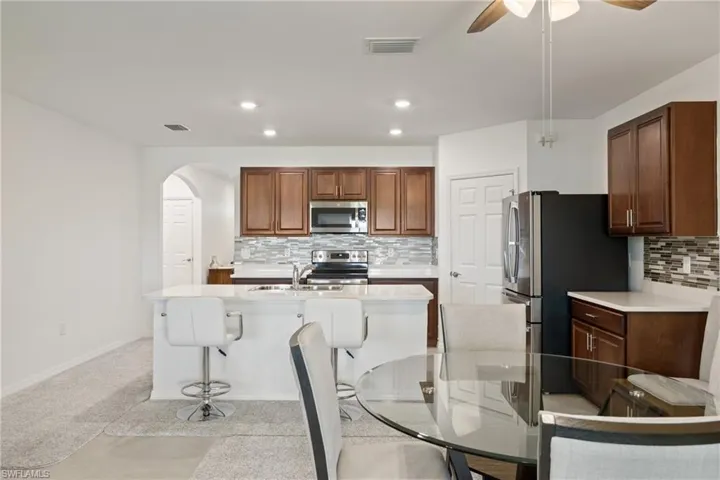 Kitchen with appliances with stainless steel finishes, an island with sink, backsplash, ceiling fan, and sink