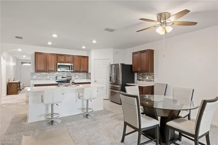 Kitchen with decorative backsplash, light tile patterned floors, stainless steel appliances, and ceiling fan