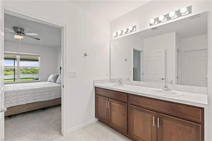 Bathroom with dual bowl vanity, ceiling fan, and tile patterned floors