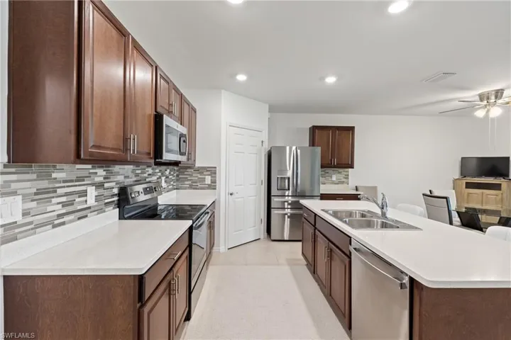 Kitchen with ceiling fan, sink, stainless steel appliances, and tasteful backsplash