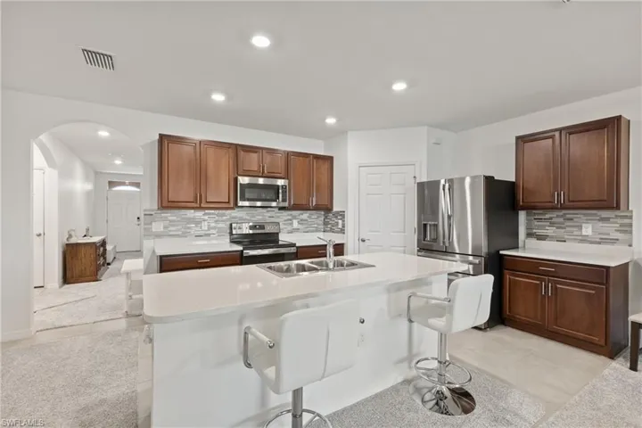 Kitchen featuring tasteful backsplash, sink, stainless steel appliances, and light tile patterned floors