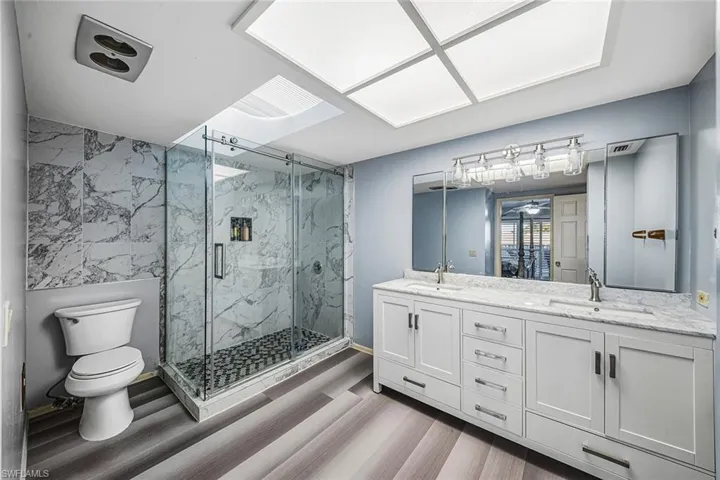 Bathroom with double vanity and a marble finish shower