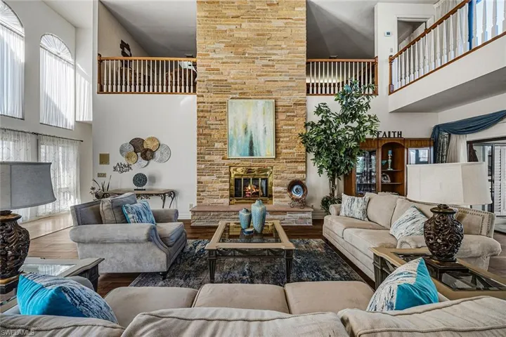 Living room featuring a towering ceiling, healthy amount of natural light, wood finished floors, and a fireplace