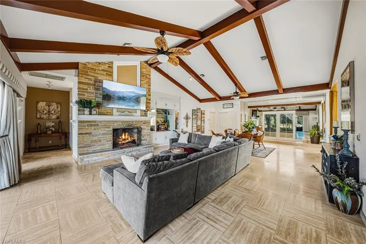 Living room featuring a fireplace, high vaulted ceiling, and beam ceiling