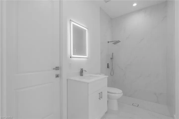Bathroom with a tile shower, vanity, and toilet