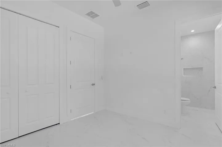 Unfurnished bedroom featuring ensuite bath, ceiling fan, and a closet